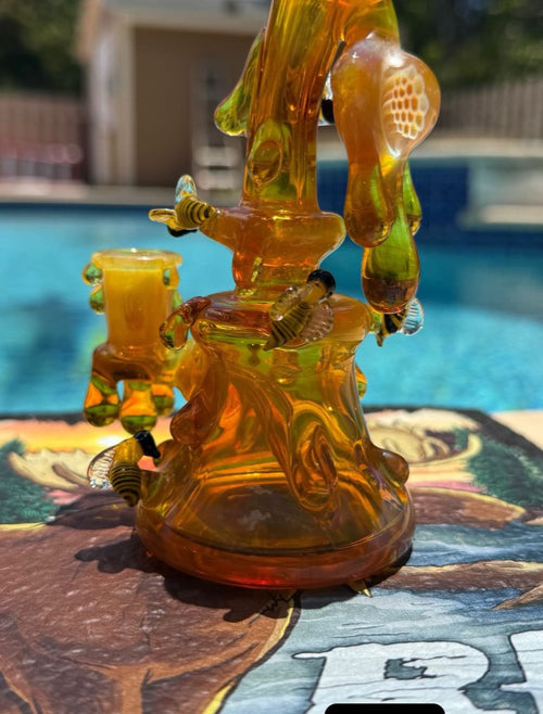 Amber and green sculptural rig with worked glass bees and a honeycomb cap, poolside in Miami