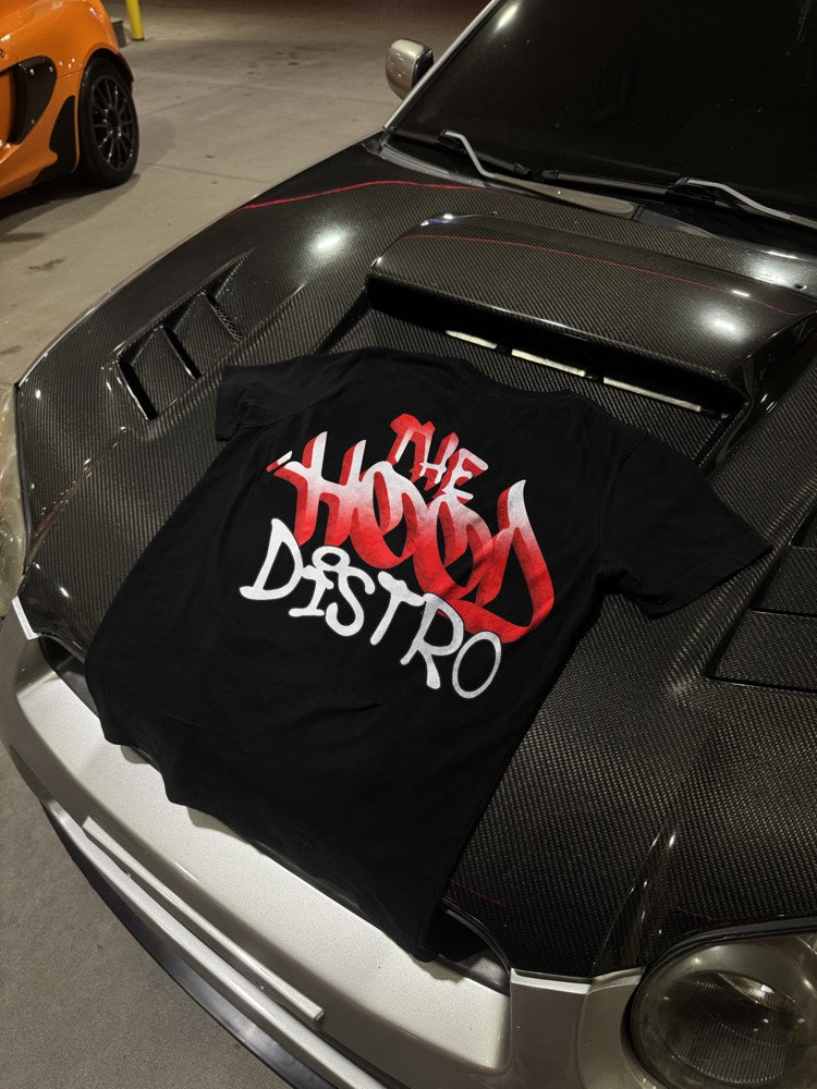 Wordmark tee on an orange supercar hood